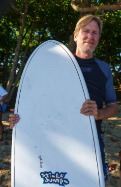 John E. Phillips on the beach with his surfboard